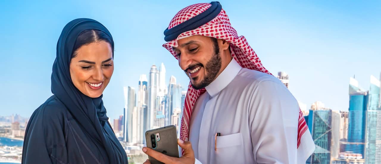 Ein Paar blickt auf ein Smartphone in Dubai